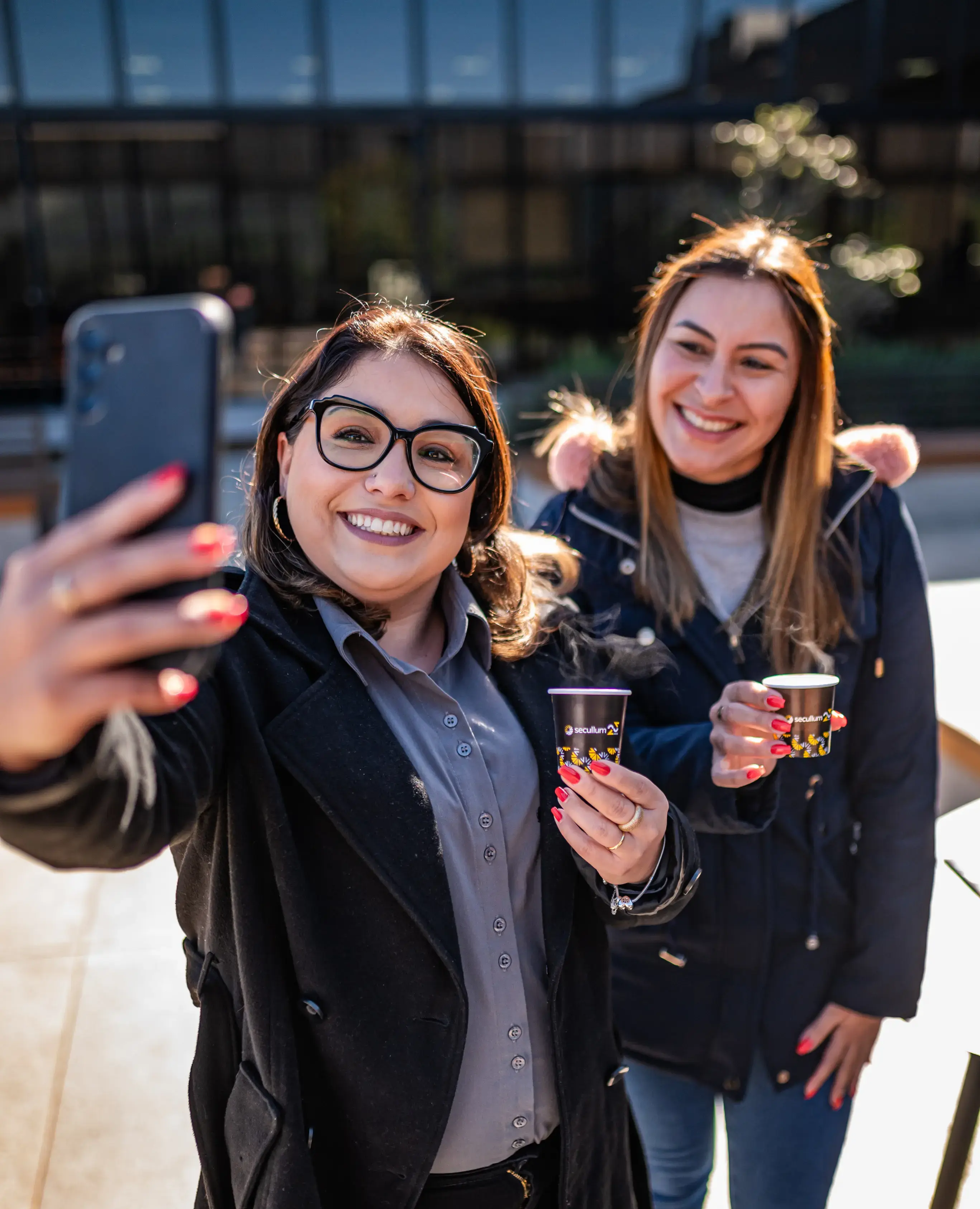 Duas funcionárias tirando uma selfie na área de convivência da empresa
