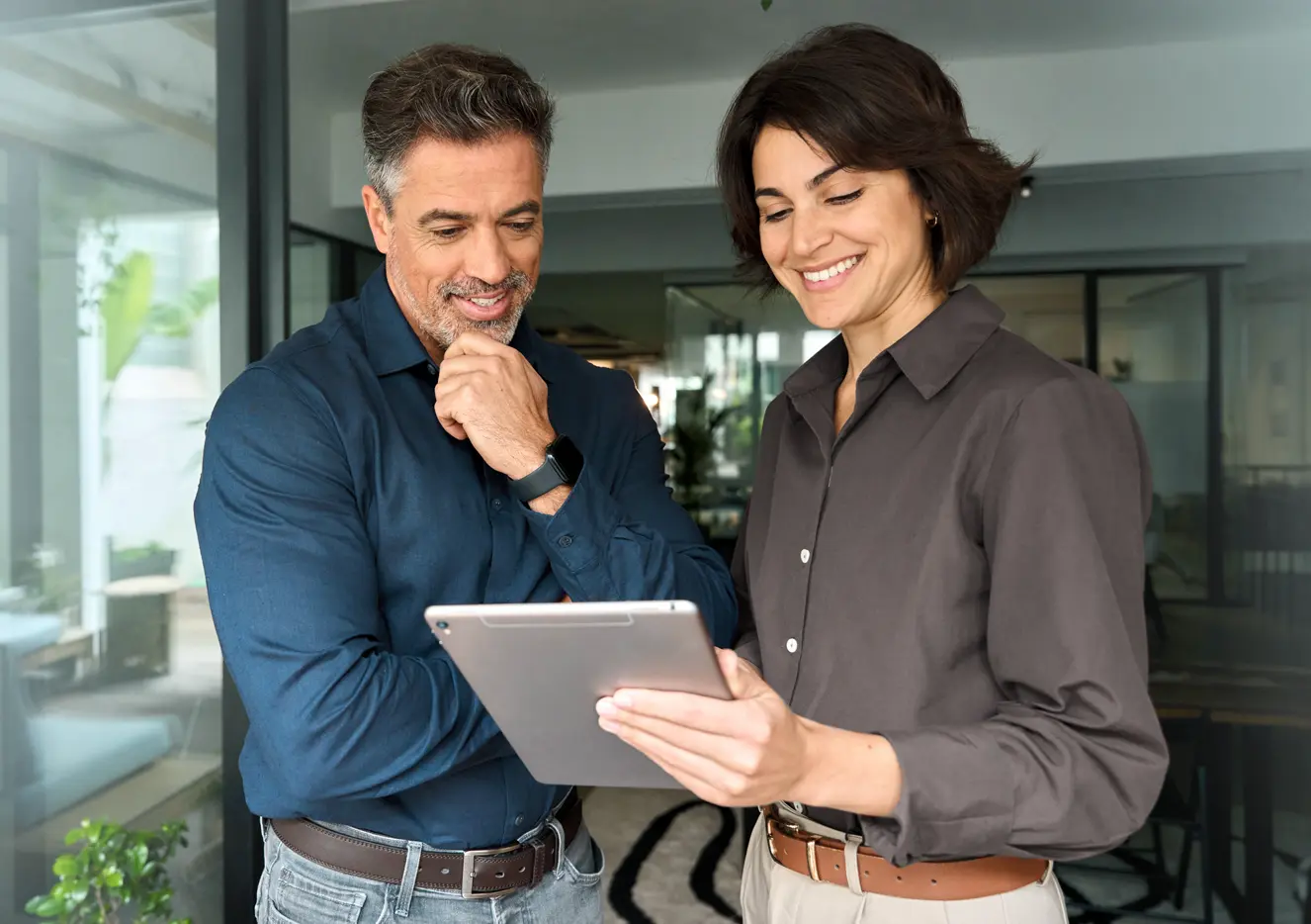 Um homem e uma mulher sorrindo olhando para um tablet